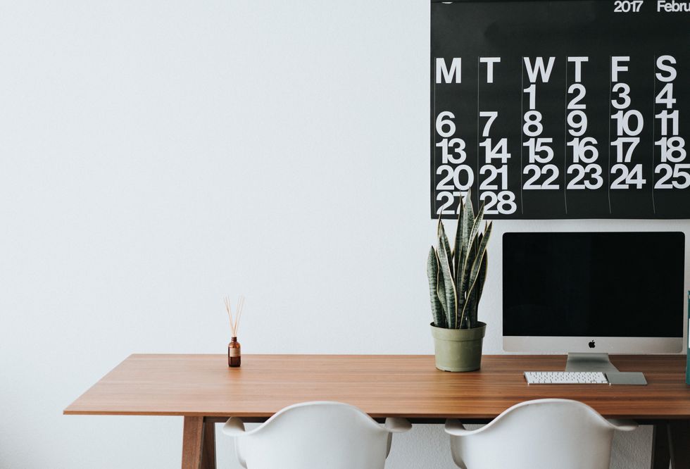 Photo of a desk in a minimalist office with a calendar and computer