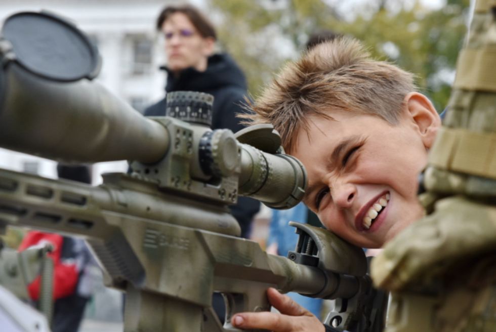 Photo of a ​boy looking through the scope of a sniper rifle in Kramatorsk, Ukraine