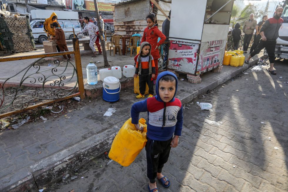 Photo of a ​Palestinian child holding a jerrycan to fill it with water.