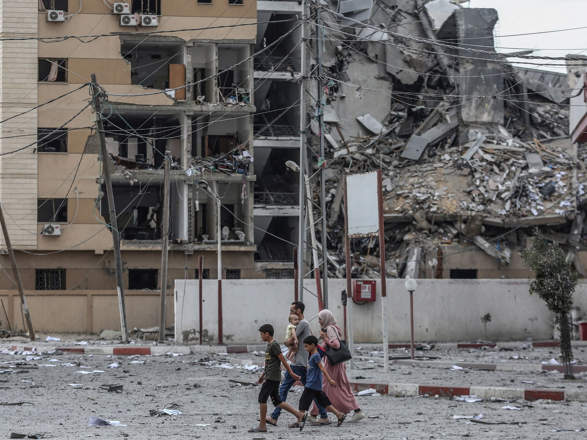 photo of a family of five walking past a bombed out building