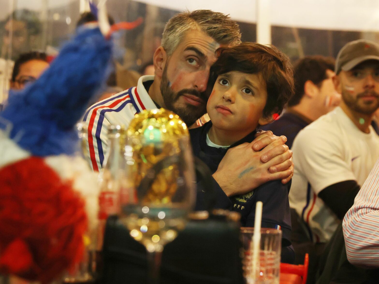 Photo of a father and his son wearing French soccer jerseys while watching a game