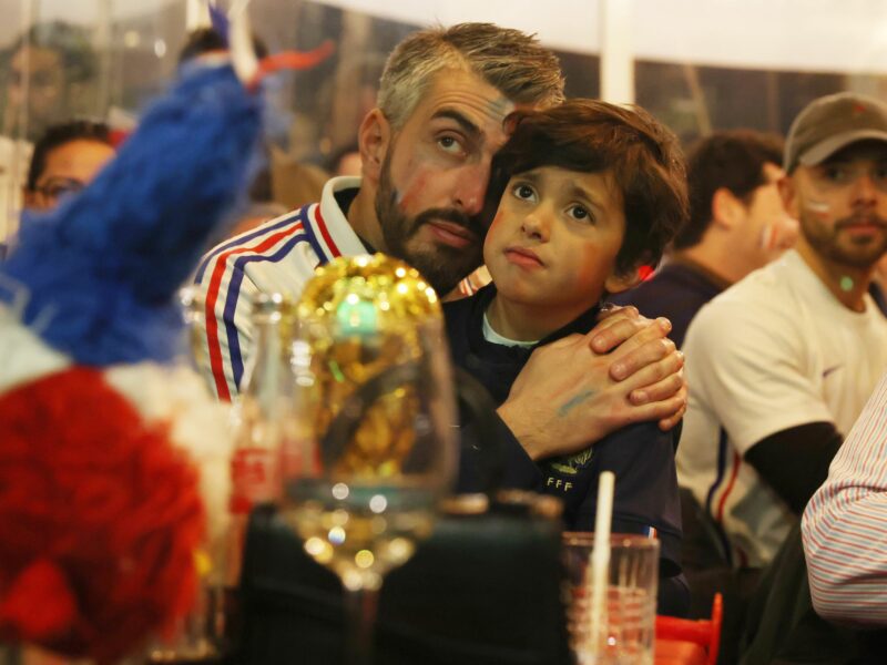 Photo of a father and his son wearing French soccer jerseys while watching a game