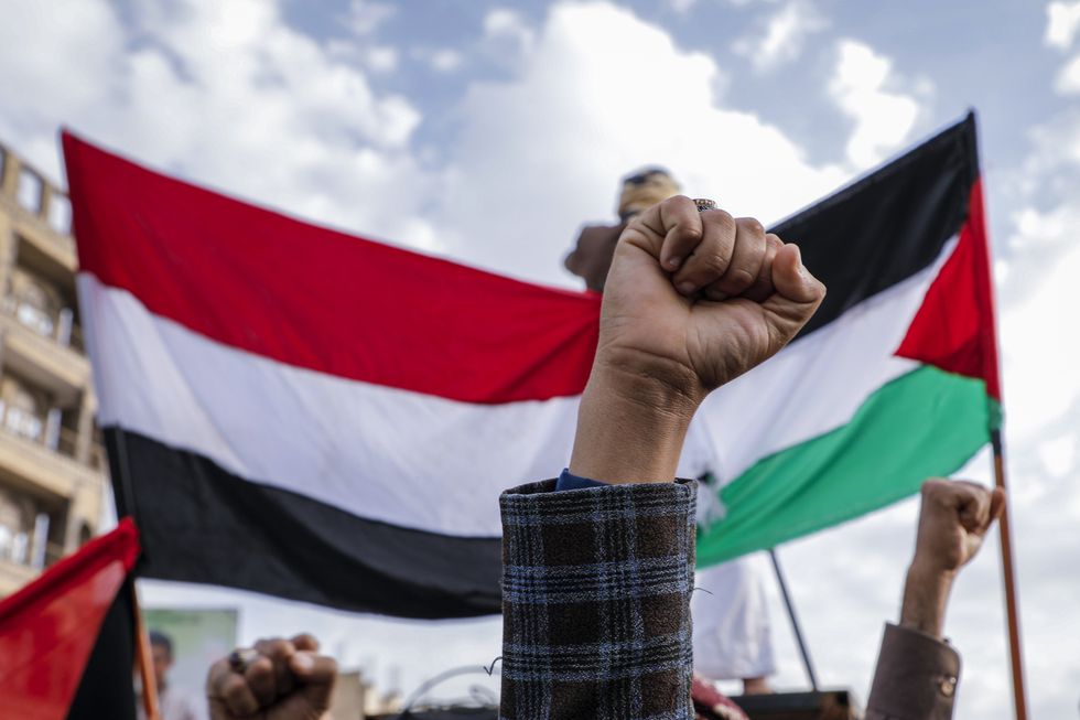 Photo of a fist raised in front of a Palestinian flag at a protest in Sana'a, Yemen, on Nov. 10