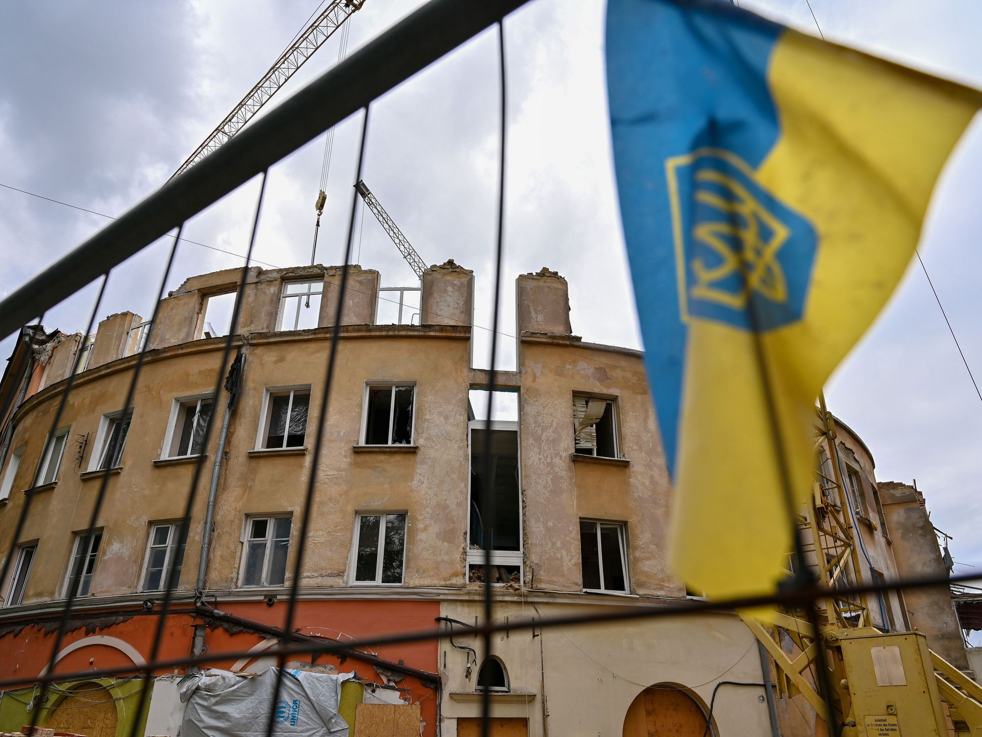 Photo of a flag of Ukraine flying in front of a partially destroyed building in Lviv, Ukraine