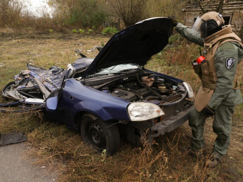 photo of a flattened car and a soldier