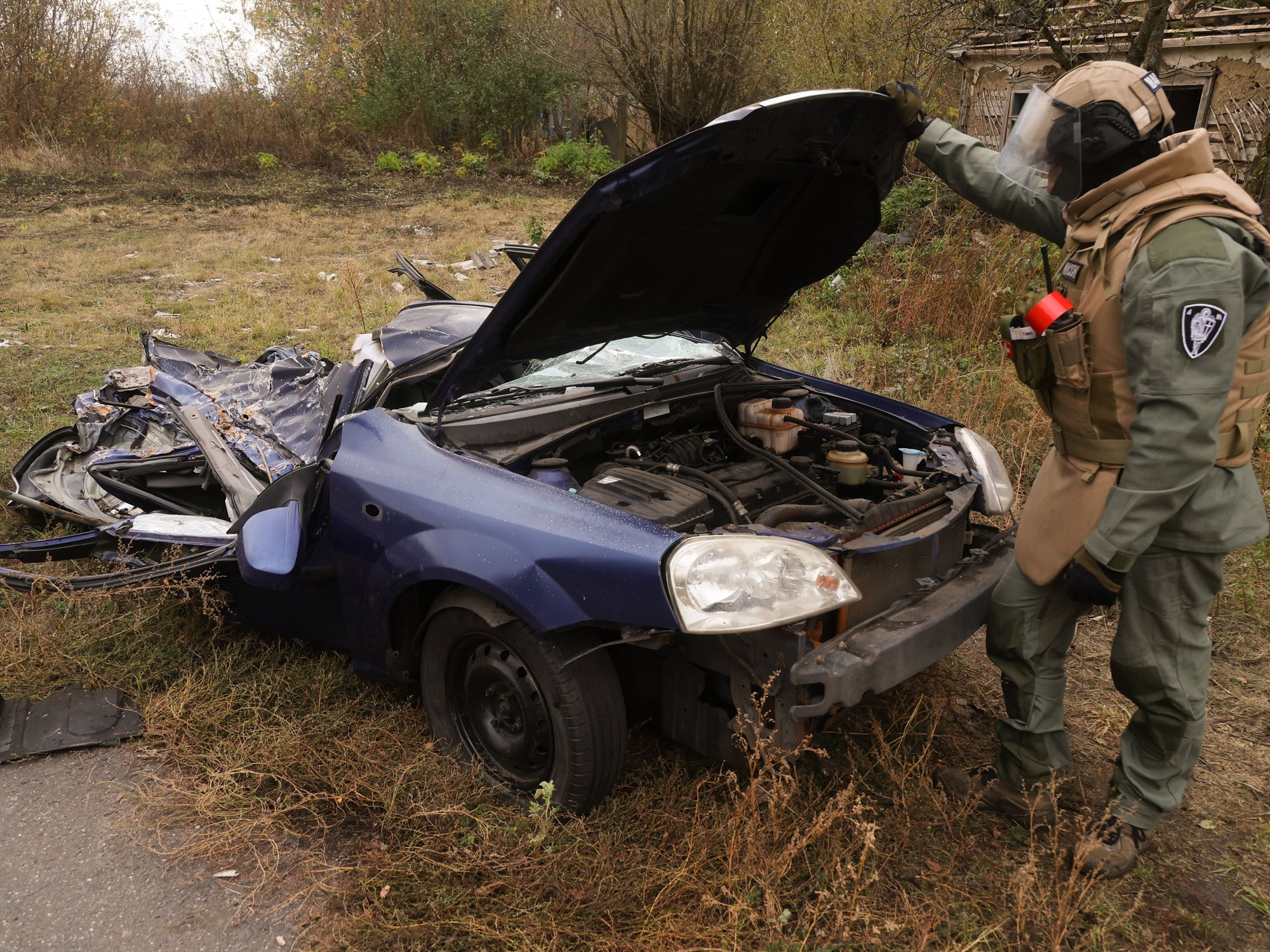 photo of a flattened car and a soldier