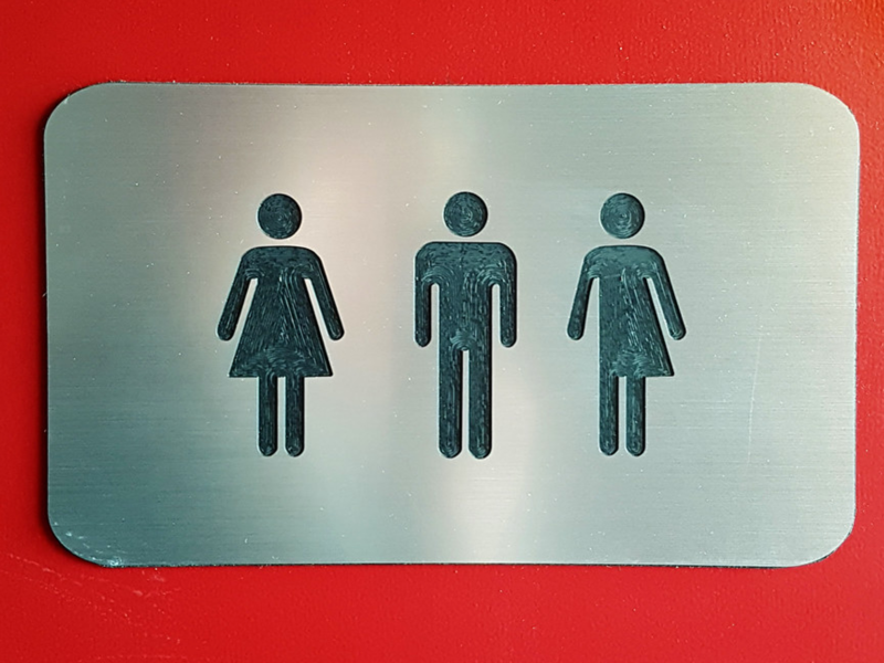 Photo of a gender-inclusive bathroom sign on a red door