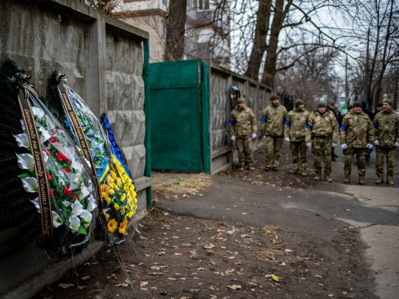 Photo of a group ​Ukrainian soldiers paying walking toward funeral wreaths for a solider killed in the battle of Bakhmut