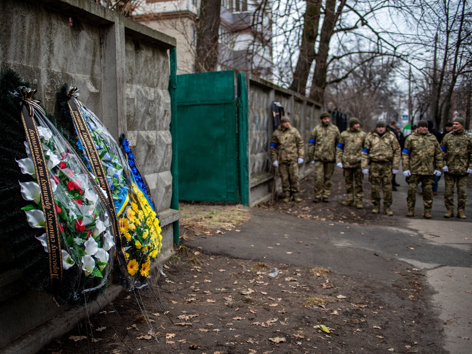 Photo of a group ​Ukrainian soldiers paying walking toward funeral wreaths for a solider killed in the battle of Bakhmut