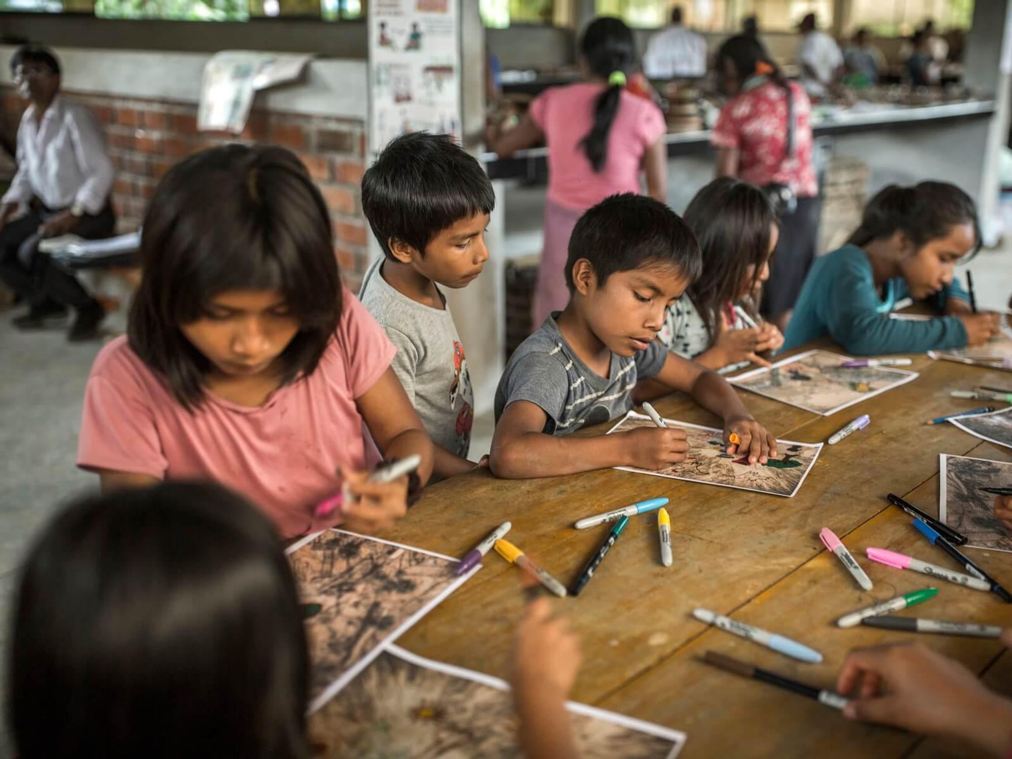 Photo of a group of children from the Awajún community participating in a workshop to draw on photographs of destroyed ecosystems in the Amazon