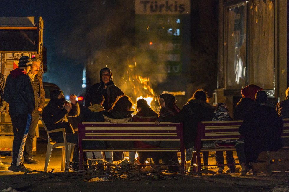 Photo of a group of people in Reyhhanli, a turkish city in the border with Syria, getting warm with fires in the streets after a fast evacuation from their homes