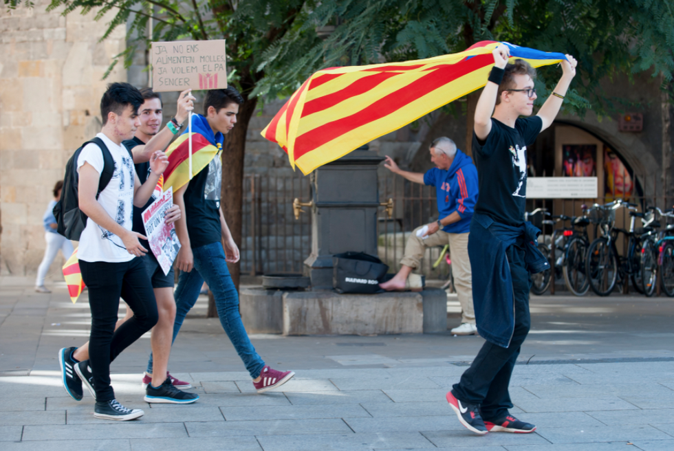 Photo of a group of students at a pro-independence rally in Barcelona, one of whom is flying the flag of Catalonia