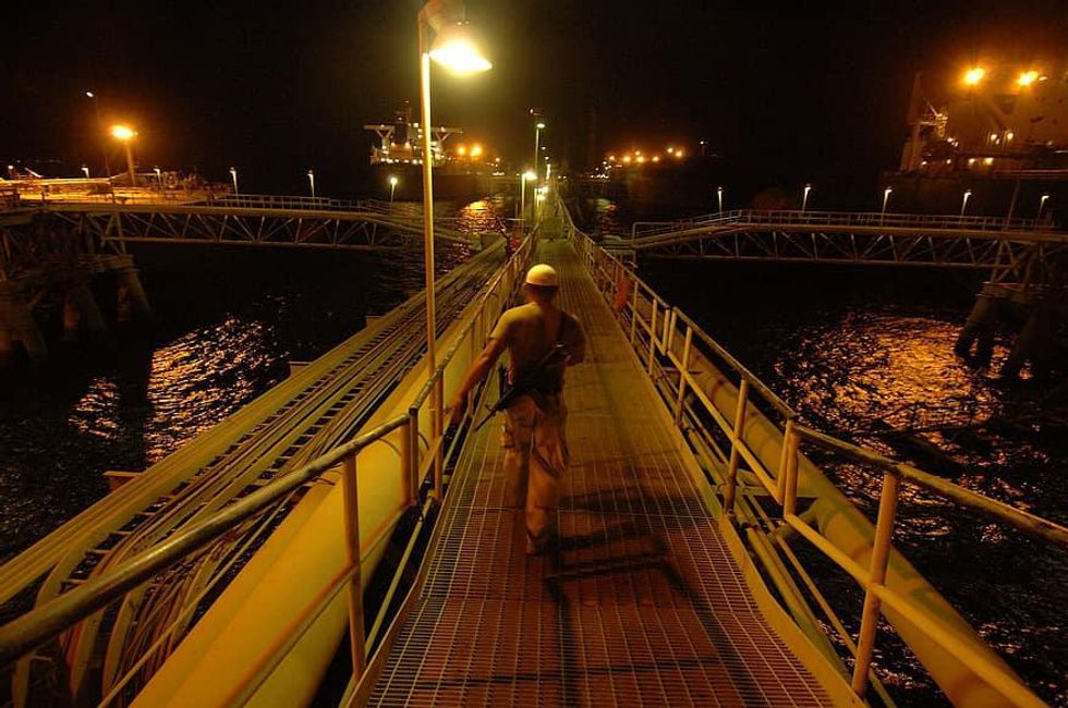 Photo of a guard walking on a bridge at an oil rig in the Persian Gulf