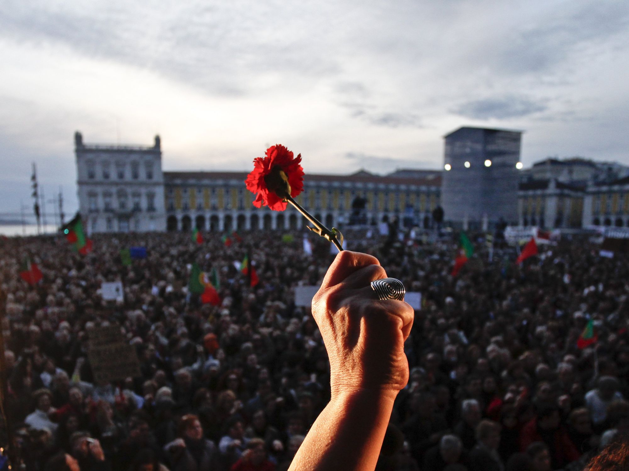 Photo of a hand brandishing a carnation flower in a crowded square in Portugal
