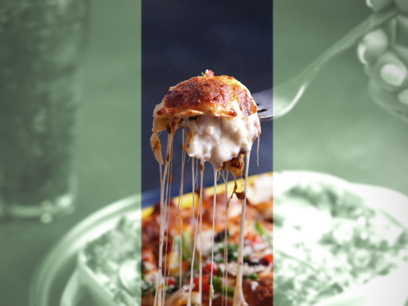 Photo of a hand holding a fork with a portion of lasagna