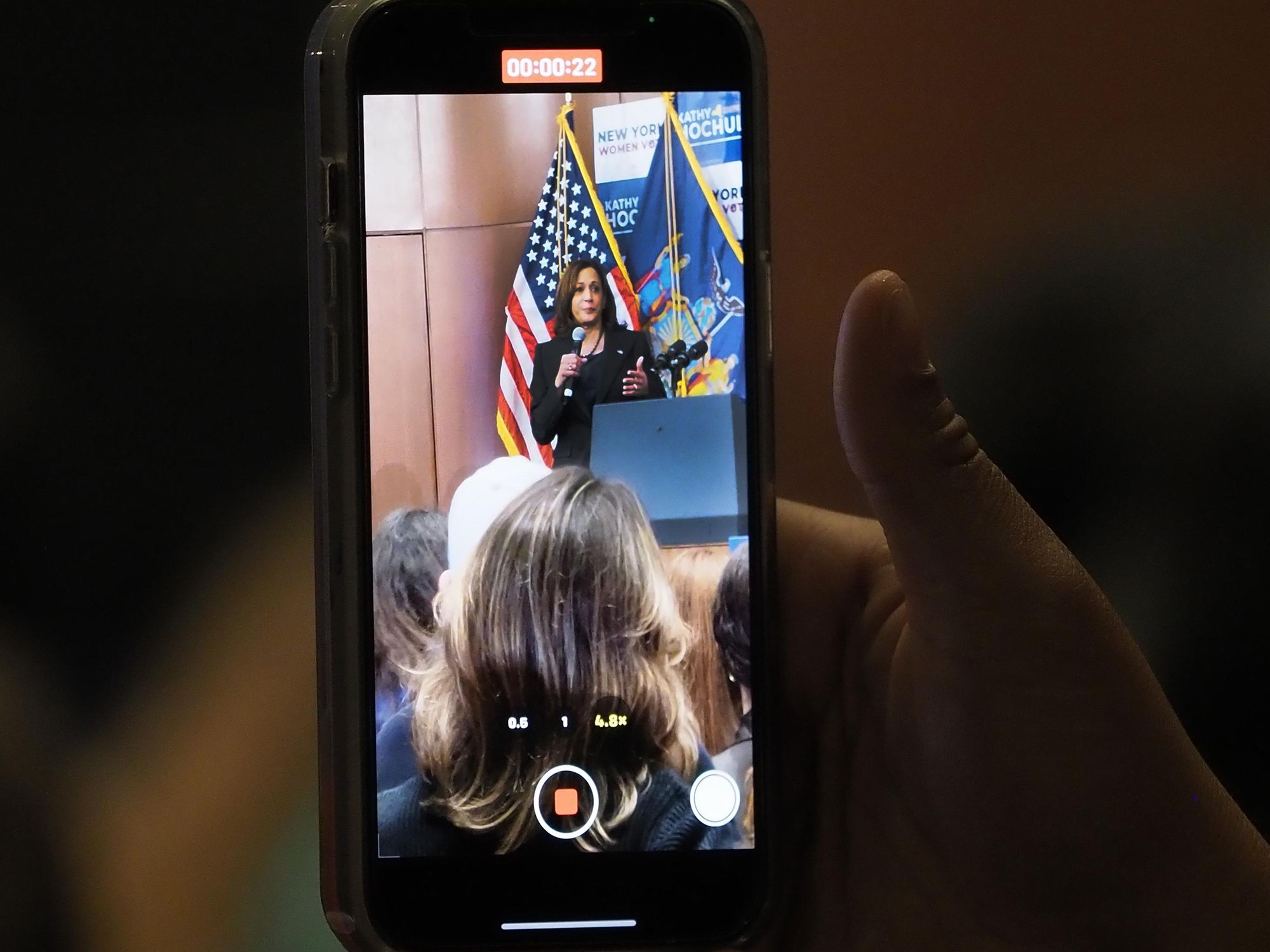 Photo of a hand holding a phone recording footage of ​Vice President Kamala Harris during a midterm rally in NYC on Nov. 3