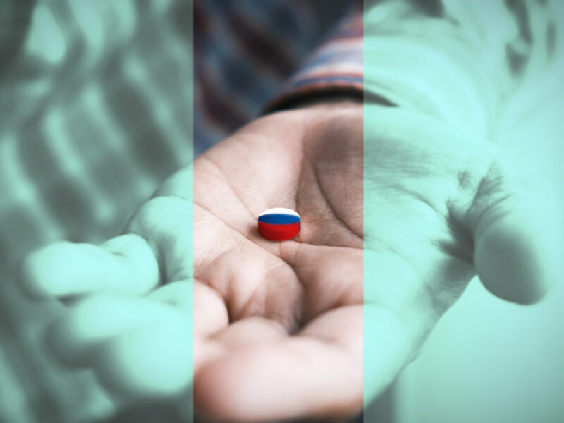 Photo of a hand holding medication with the white blue red colors of the Russian flag