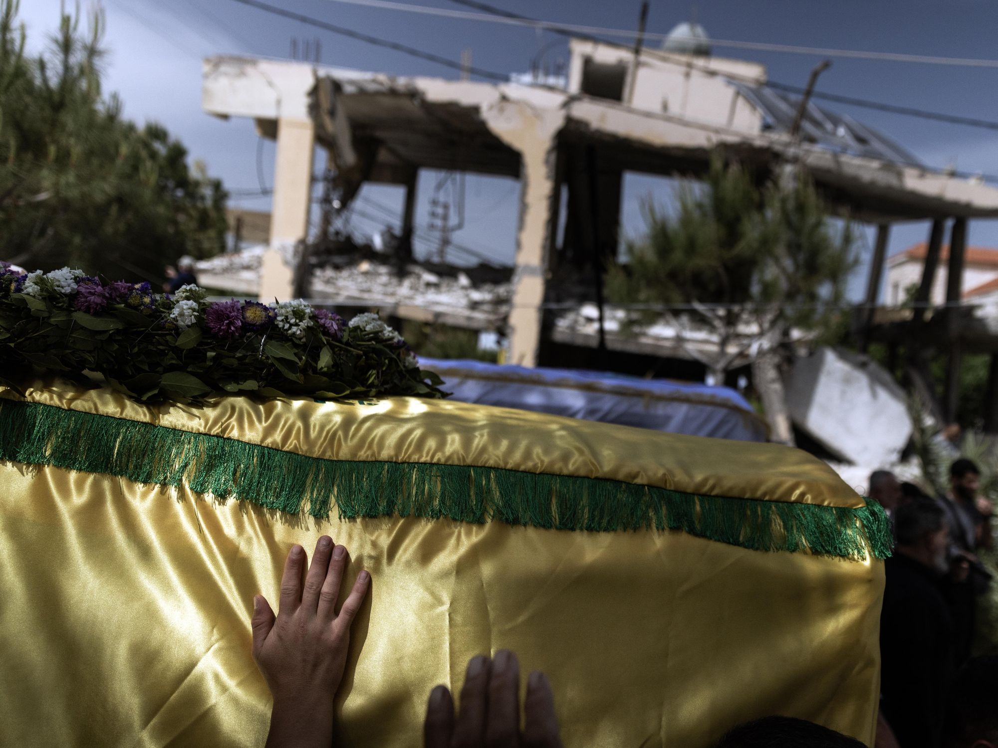 Photo of a hand touching the casket carrying Haj Maryam Qashqash during her funeral procession: she and her ten year old niece were both killed on April 23rd by an Israeli rocket that targeted their family home in southern Lebanon.