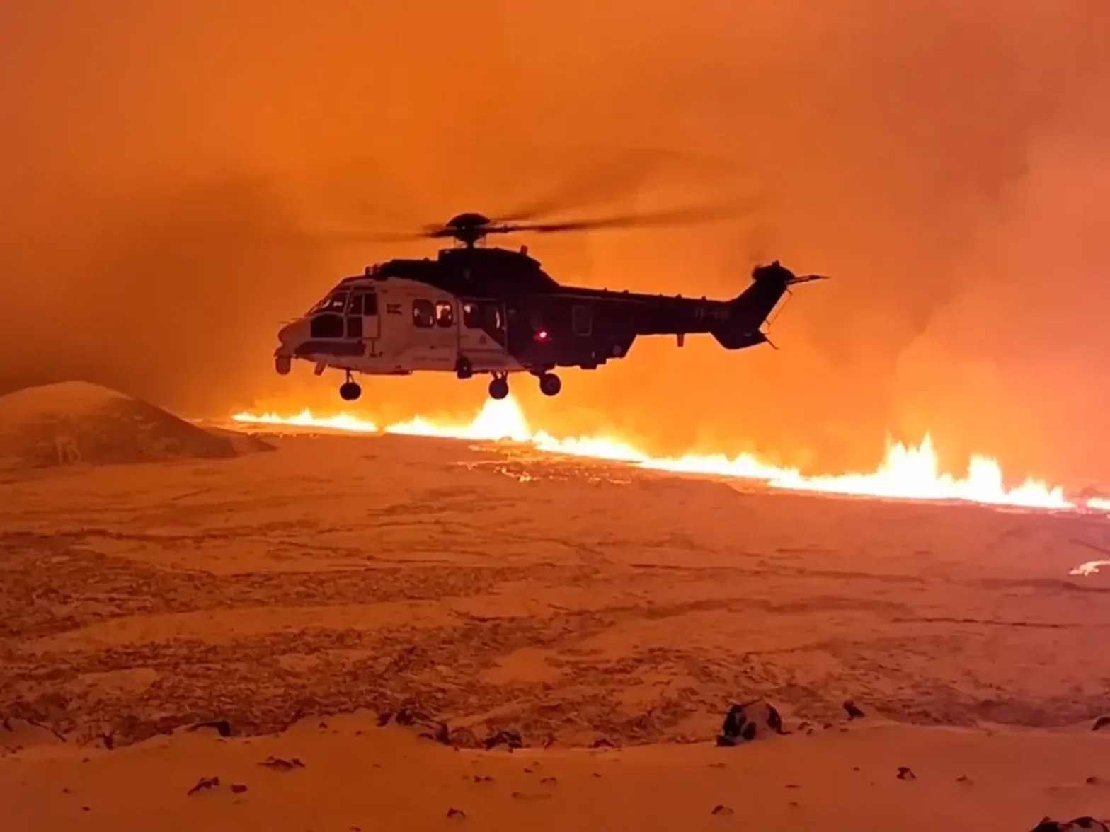photo of a helicopter flying above fire and lava of a volcano