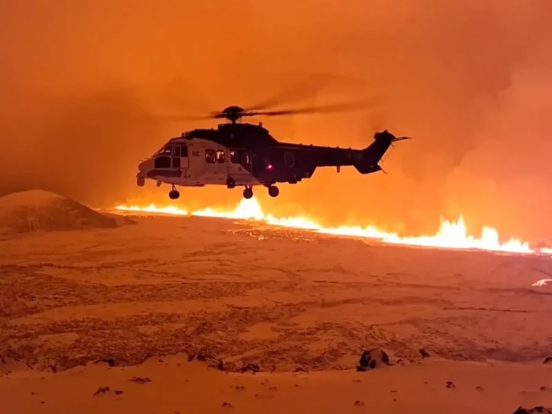 photo of a helicopter flying above fire and lava of a volcano