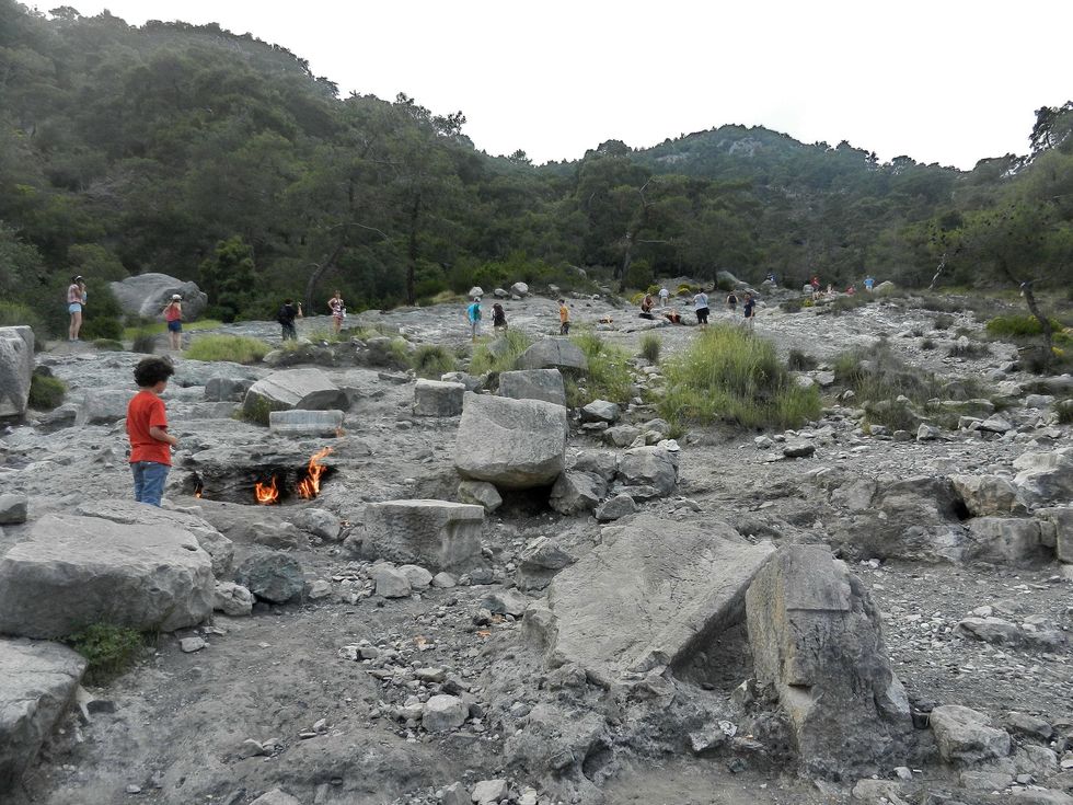 Photo of a kid standing next to Yanartas's Mount Chimaera eternal fire