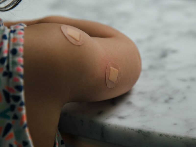 Photo of a kid's arm with bandaids following vaccination