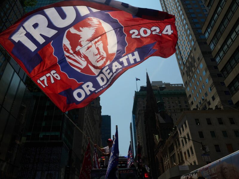 Photo of a large "Trump or Death" flag waved outside Trump Tower in New York City at a rally honoring former president Donald Trump the day after being shot at in an assassination attempt while speaking at a Pennsylvania rally.
