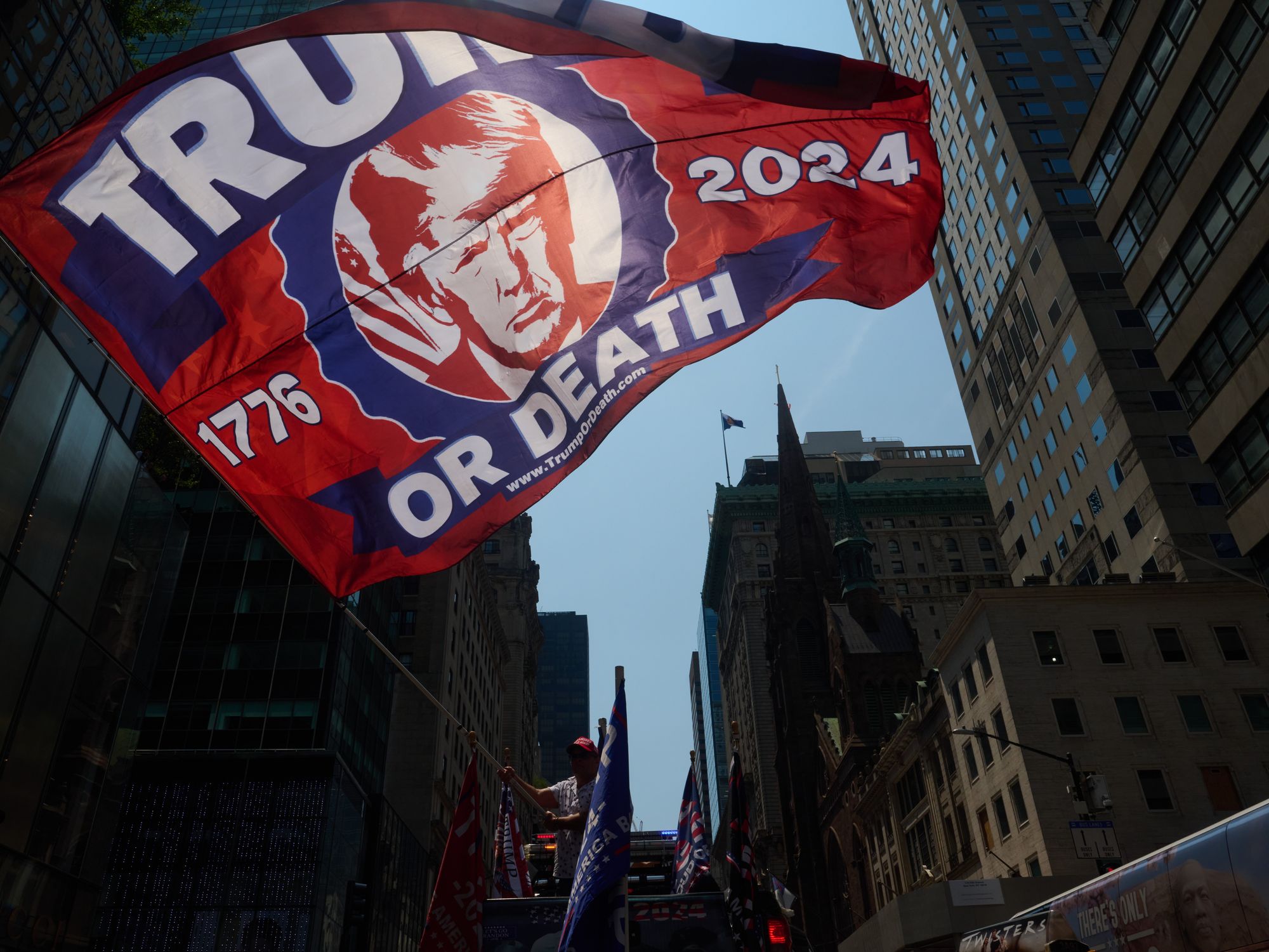 Photo of a large "Trump or Death" flag waved outside Trump Tower in New York City at a rally honoring former president Donald Trump the day after being shot at in an assassination attempt while speaking at a Pennsylvania rally.