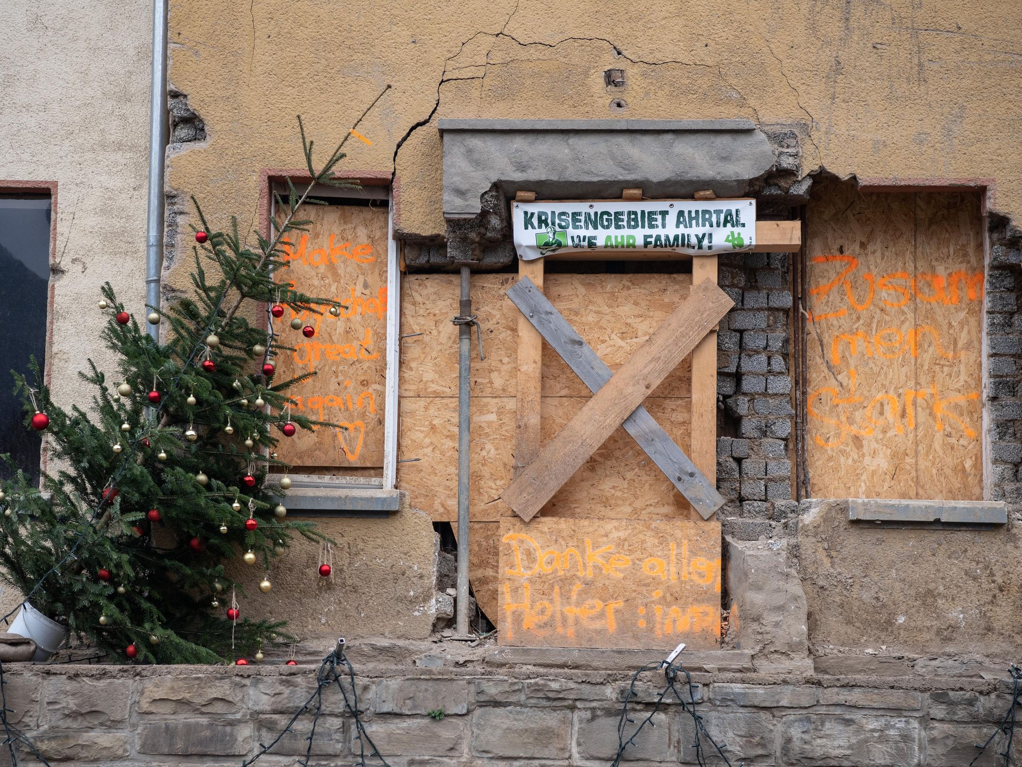 Photo of a leaning Christmas tree next to a barricaded house in deserted Mayschoss, Germany, a village hit by a flood disaster in July