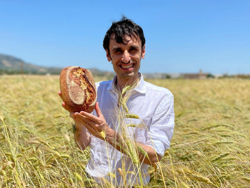 photo of a man carrying bread in a field