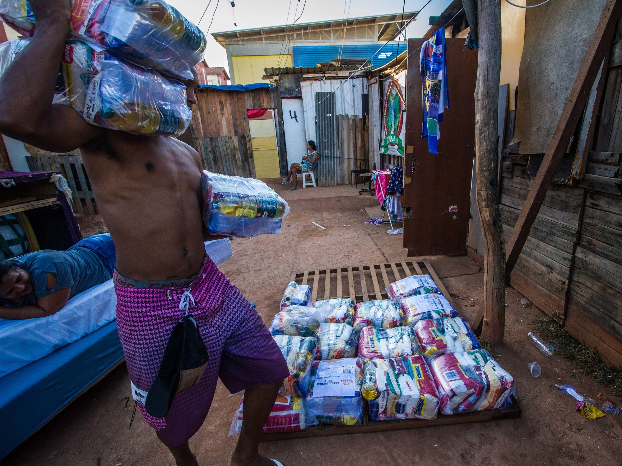 Photo of a man carrying food packages as residents of a favela in Santa Cruz, Brazil, receive aid.