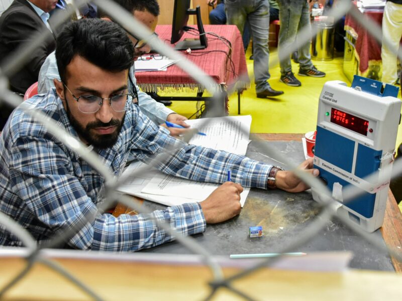 photo of a man counting votes with an electronic voting machine