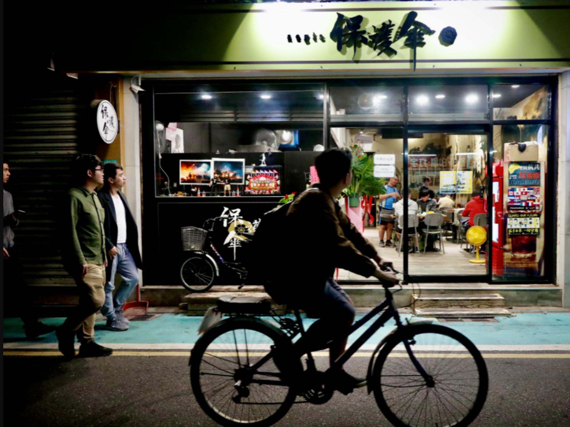 Photo of a man cycling past a store in Taipei, Taiwan