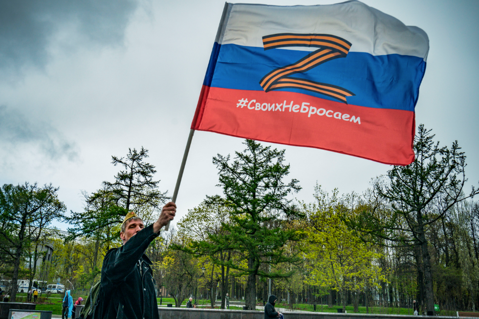 Photo of a man flying a Russian flag with the ''Z'' symbol on it.