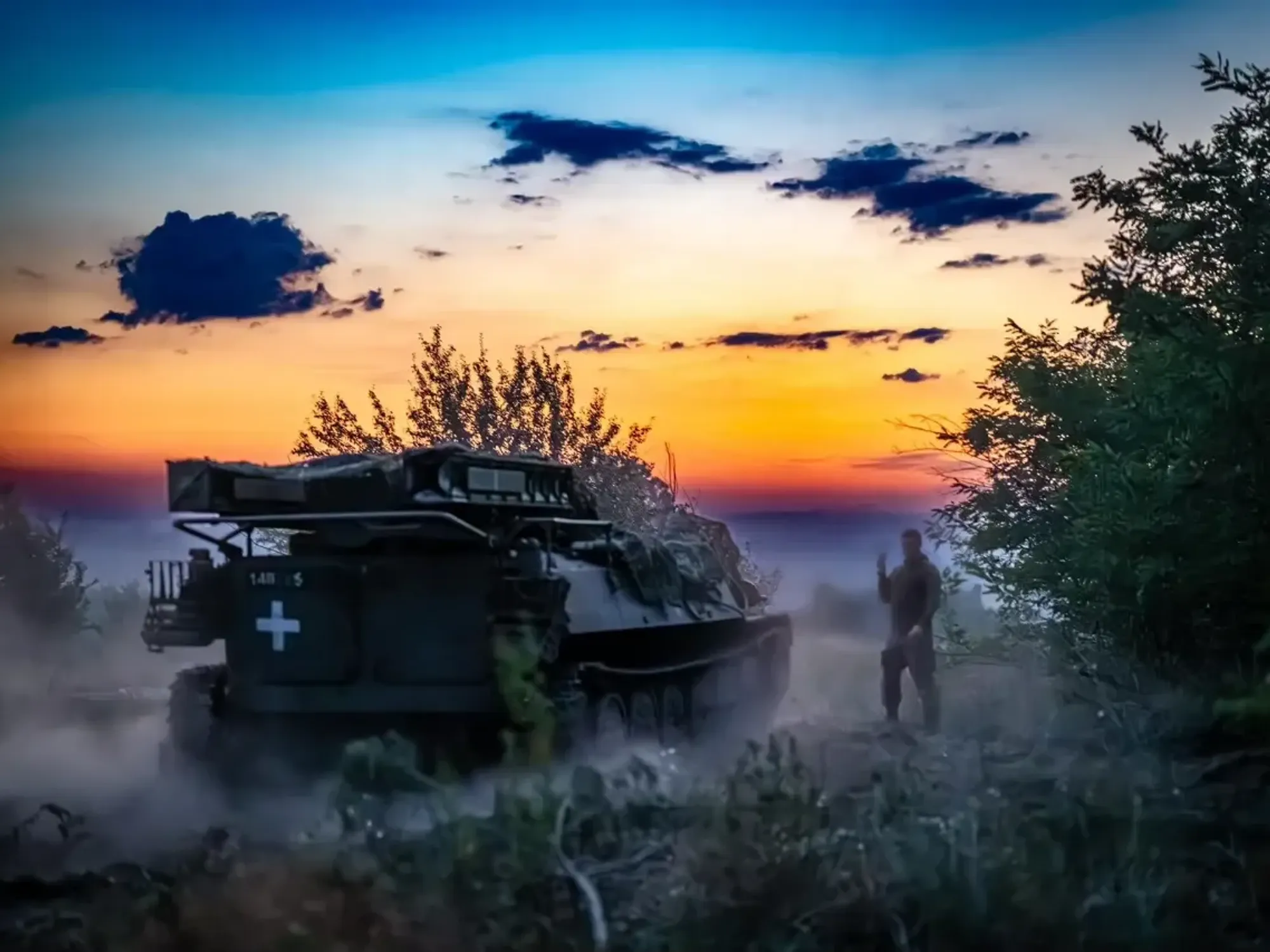 Photo of a man guiding a Ukrainian tank at dawn