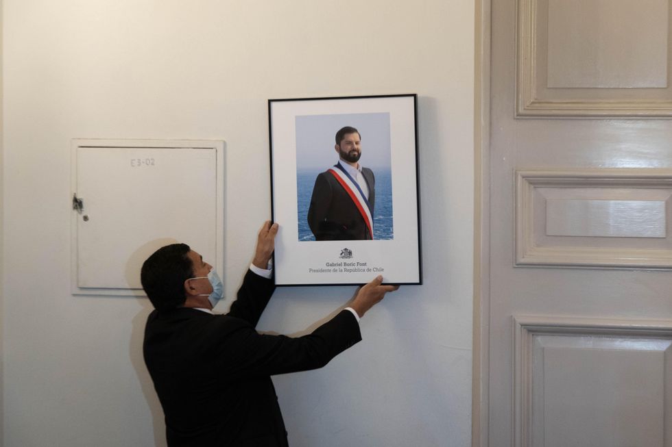 Photo of a man hanging up a portrait of President Boric in Santiago, Chile