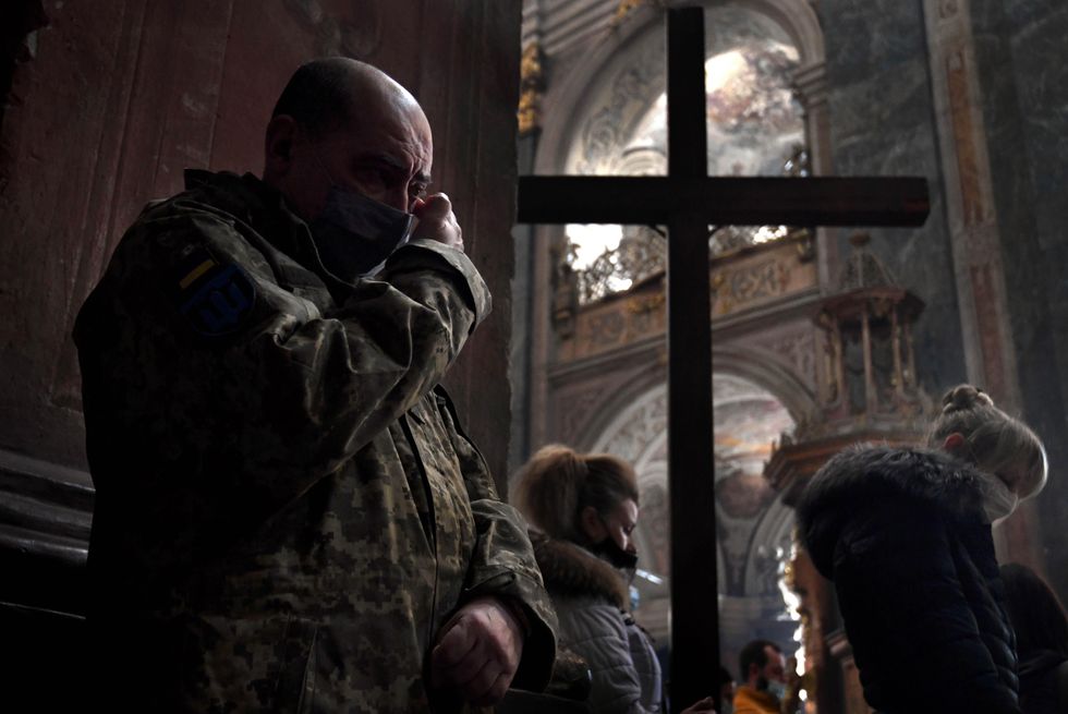 Photo of a man in a military jacket crying during a prayer at Church of the Most Holy Apostles Peter and Paul in Lviv, Ukraine