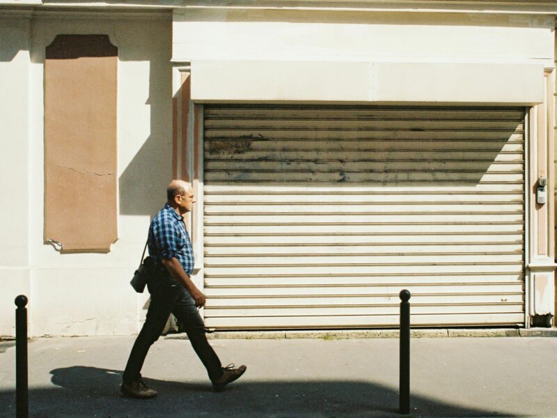 Photo of a man in France walking past a closed shop