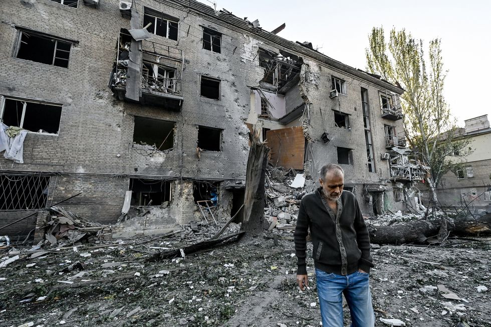 photo of a man in front of a bombed-out building