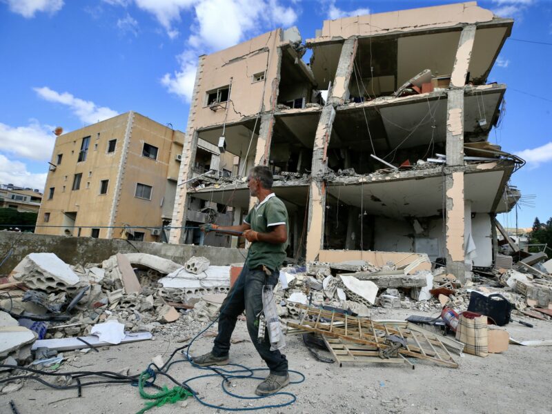 photo of a man in front of destroyed building