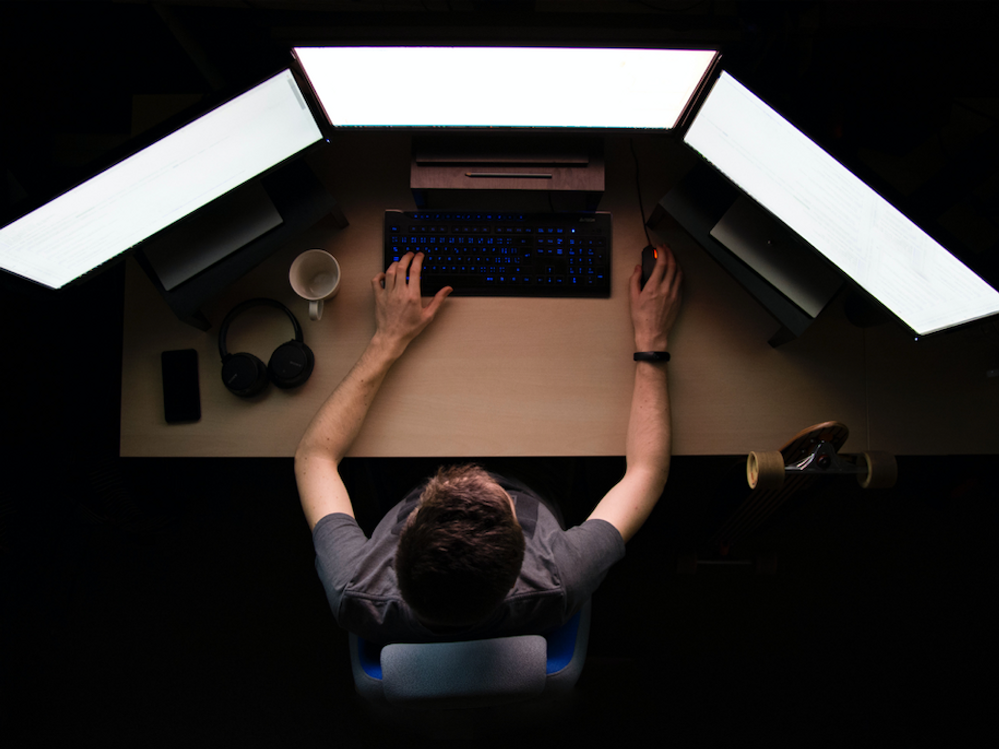 Photo of a man in front of three computer screens