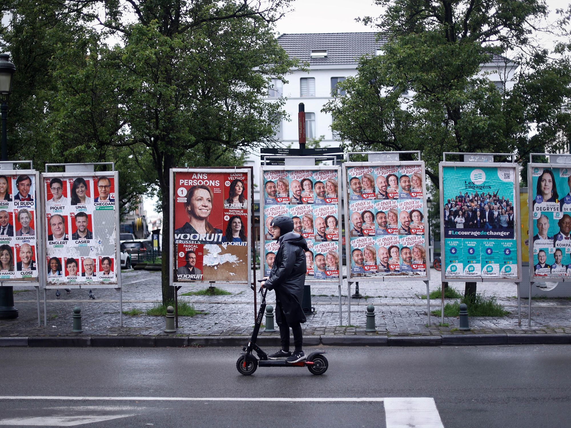 Photo of a man on an electric scooter riding past election posters in Brussels, Belgium, on May 16