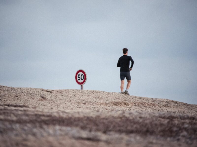 Photo of a man running next to a road sign that reads 50