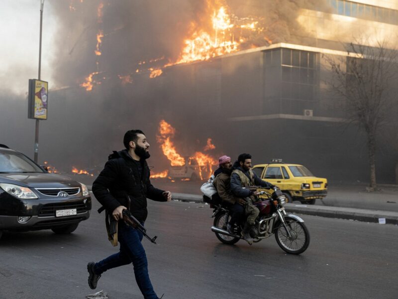 photo of a man running with a gun, a motorcycle and fire