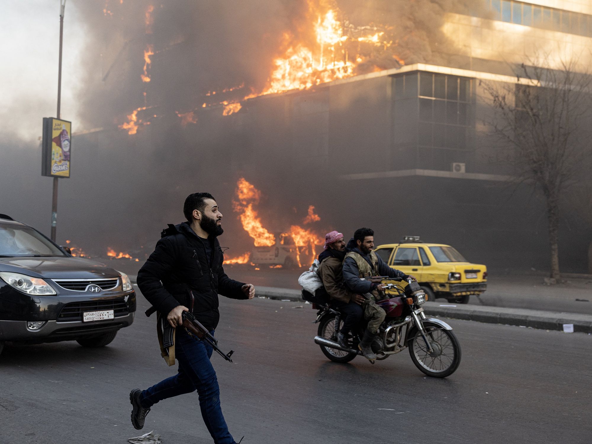 photo of a man running with a gun, a motorcycle and fire