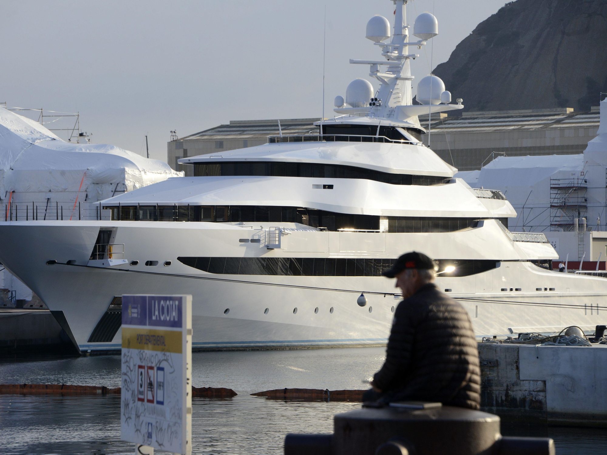 photo of a man sitting in front of a yacht