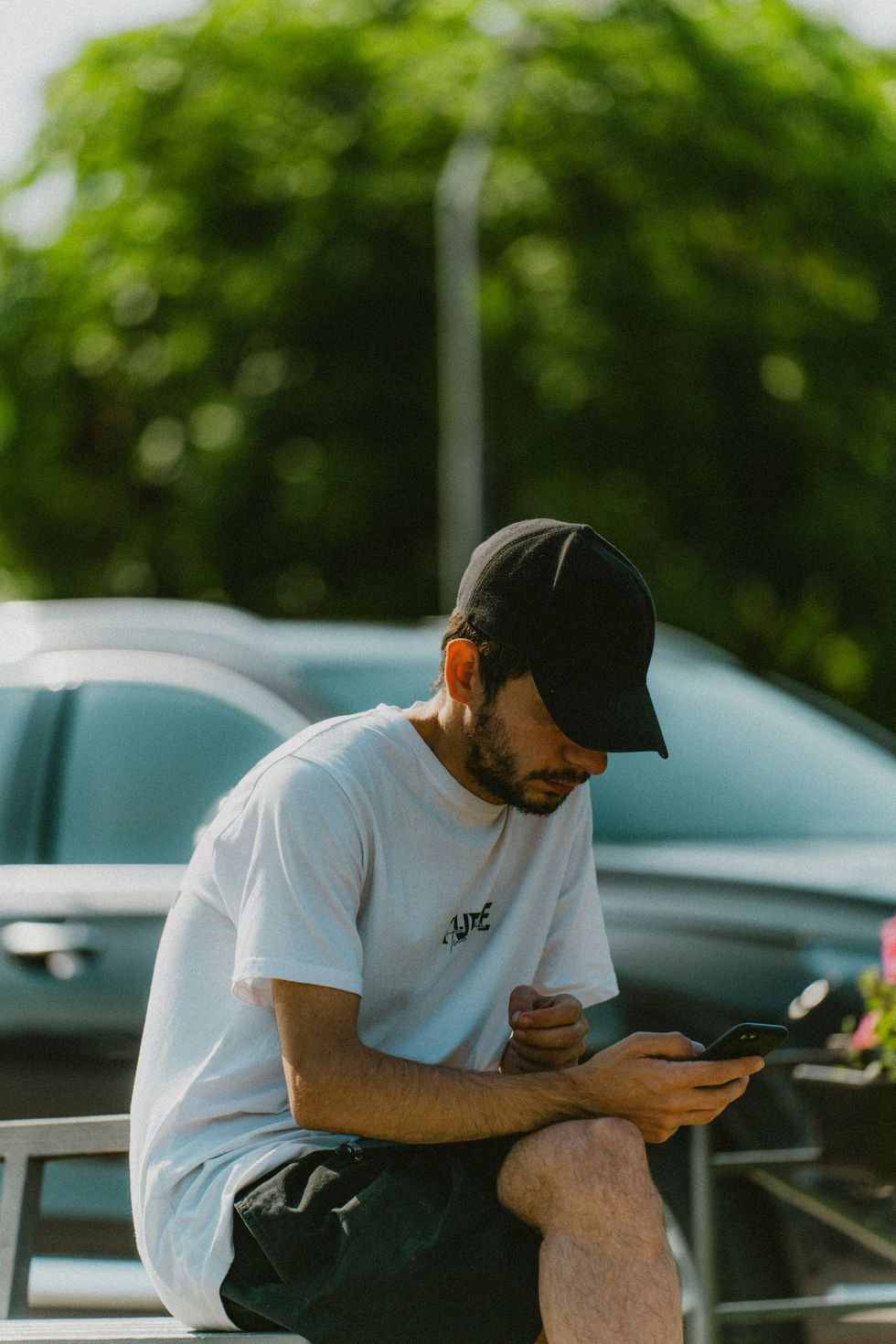 Photo of a man sitting on a bench with his phone.
