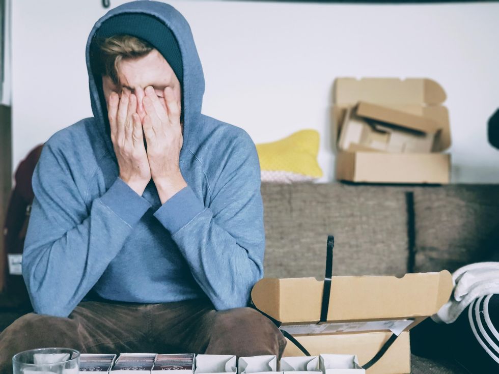 Photo of a man sitting on a couch with his head in his hands