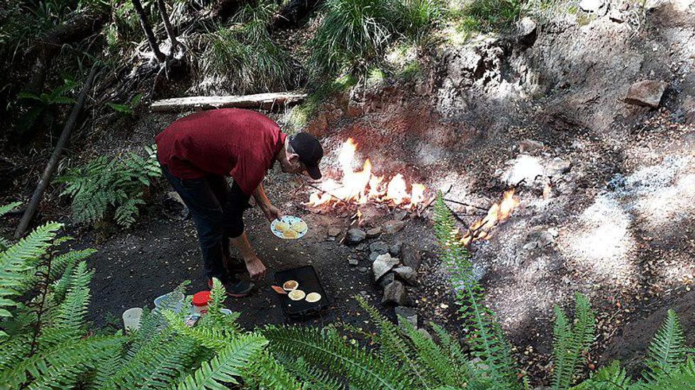 Photo of a man standing next to eternal flames at Murchison, New Zeland