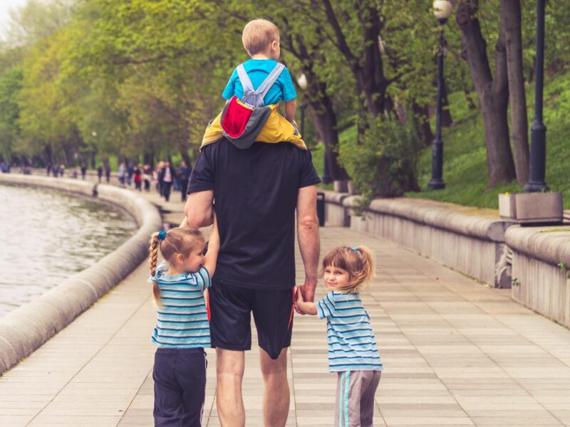 Photo of a man walking in the park with his three children
